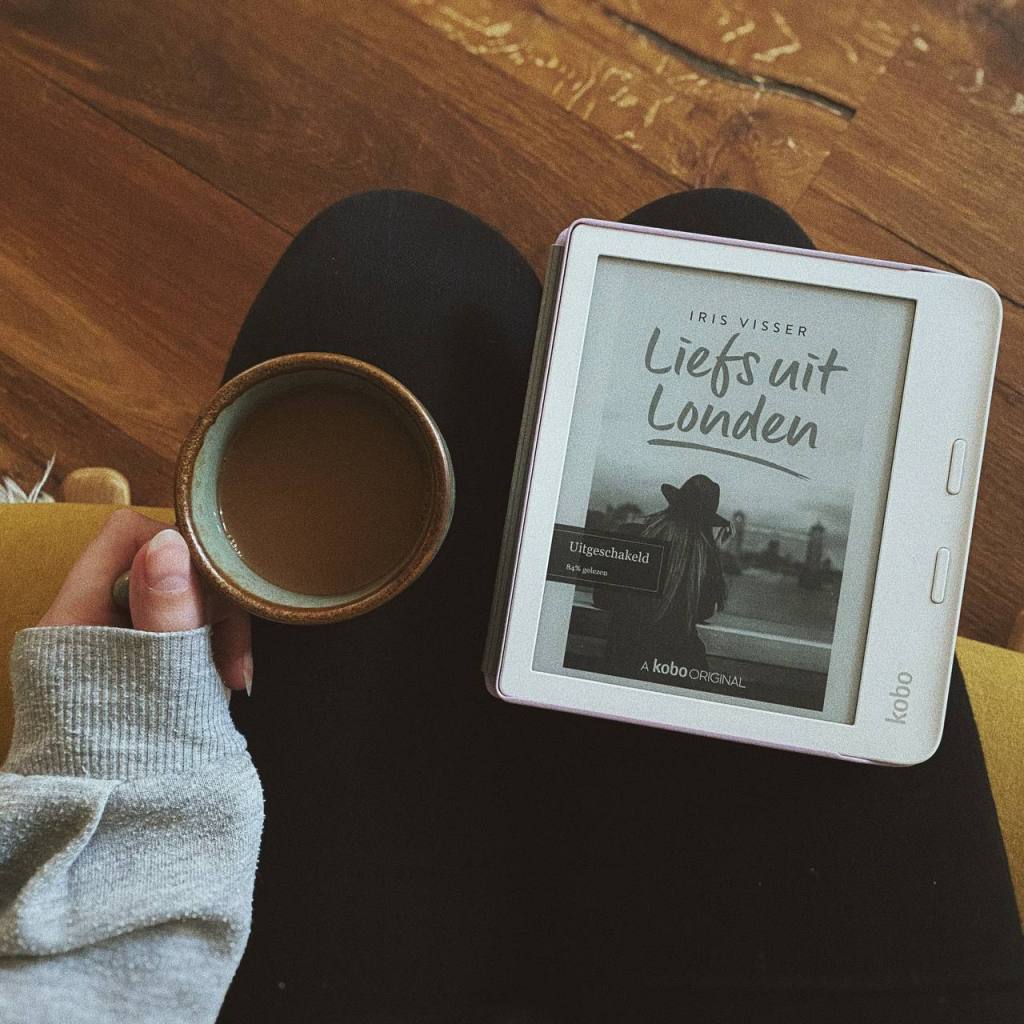Het ebook van Liefs uit Londen van Iris Visser op mijn kobo die op mijn schoot ligt. Daarnaast houd ik met mijn linkerhand een kopje koffie met melk vast.