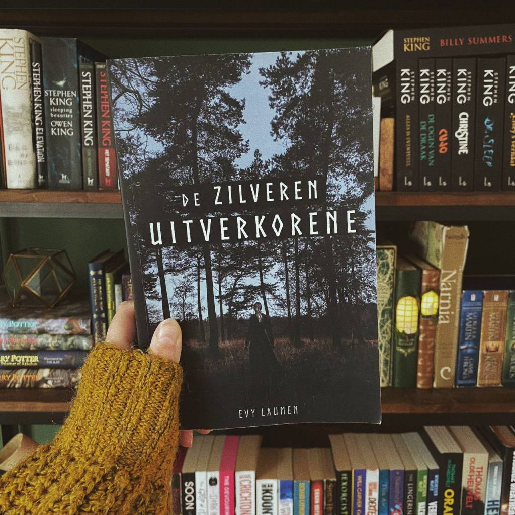 Ik houd het boek De Zilveren Uitverkorene van Evy Laumen vast voor mijn boekenkast.