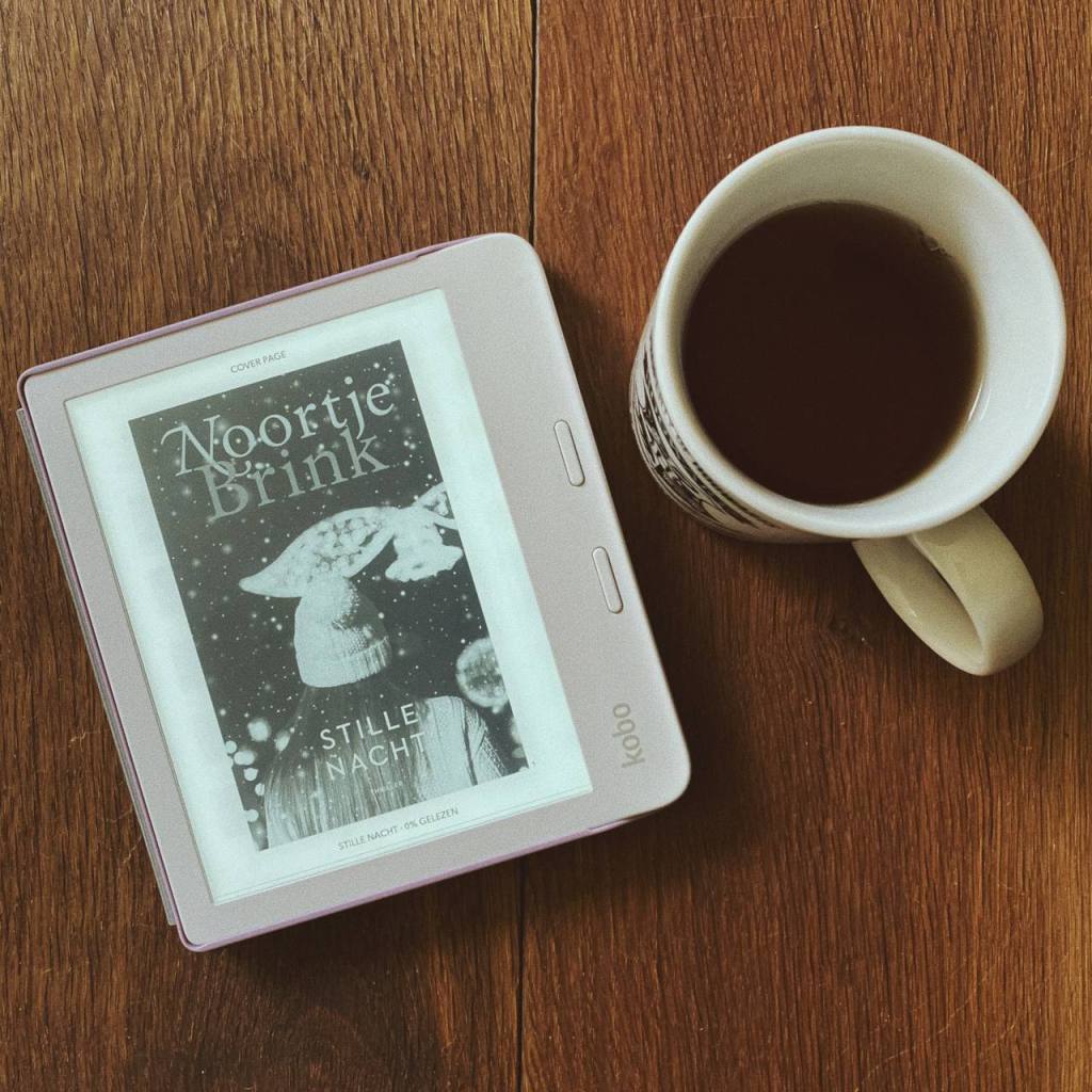 Ereader met het omslag van Stille nacht van Noortje Brink met daarnaast een grote mok thee.